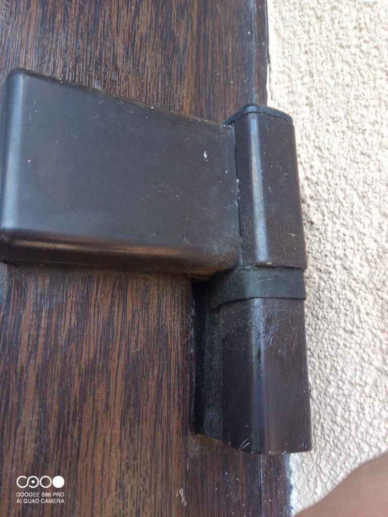 Detail pántového mechanizmu vchodových PVC dverí počas servisnej práce
